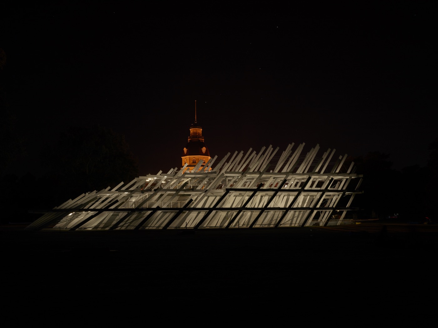 Pavillon im Schlossgarten Karlsruhe KA300 Stadtjubiläum, Nachtansicht mit reduzierter Beleuchtung und dem Schloss im Hintergrund